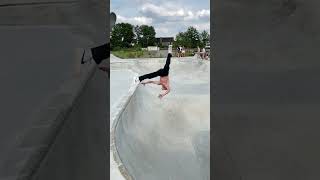 Skateboarder rides around bowl at skatepark then goes up ramp and faceplants (Slow motion)