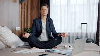 Businesswoman relaxing in lotus pose on hotel bed meditating enjoying rest