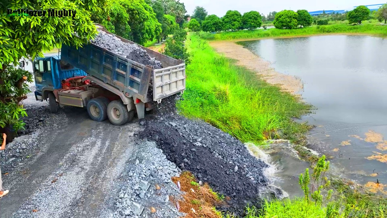 Road​ Construction, Operator Bulldozer KOMATSU D31P push Stone Into water, Dump Truck Unloading