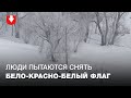 Люди в спецодежде пытаются снять бело-красно-белый флаг в Малиновке 2 февраля