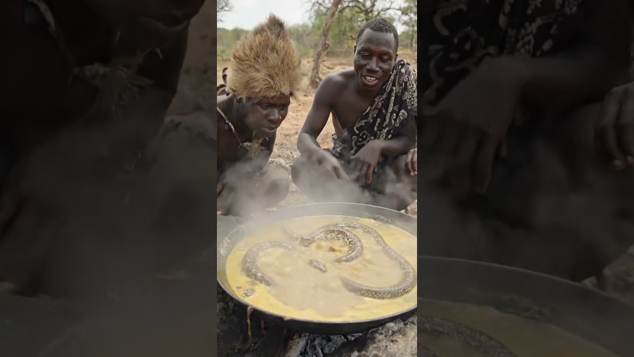 Hadzabe eating smoky campfire food under the trees.