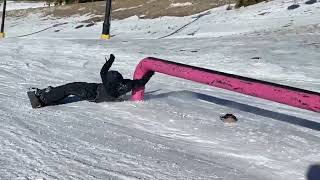 Snowboarder grinds rail and does a 360 then lands on his stomach