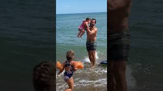 Guy pushes his little girl on boogie board at beach then wave crashes and she falls over