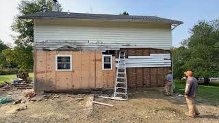 Removing old wood siding on a 1840 house with brick insulation.