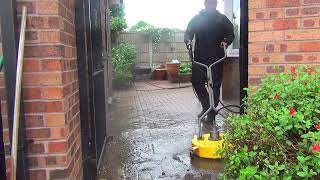 Pressure washing a blocked paved back patio in the pouring rain..