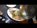 Pouring sizzling oil and soy sauce over a steamed fish