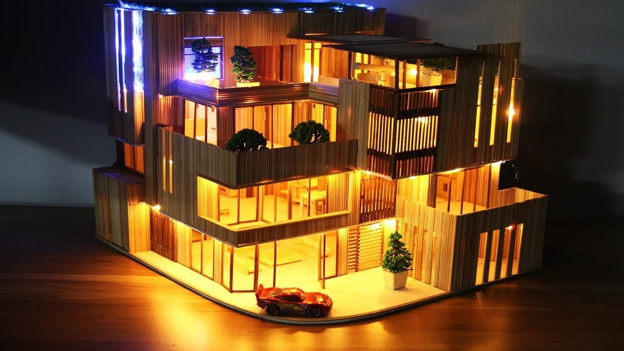 Casa en miniatura con palitos de madera y luces LED