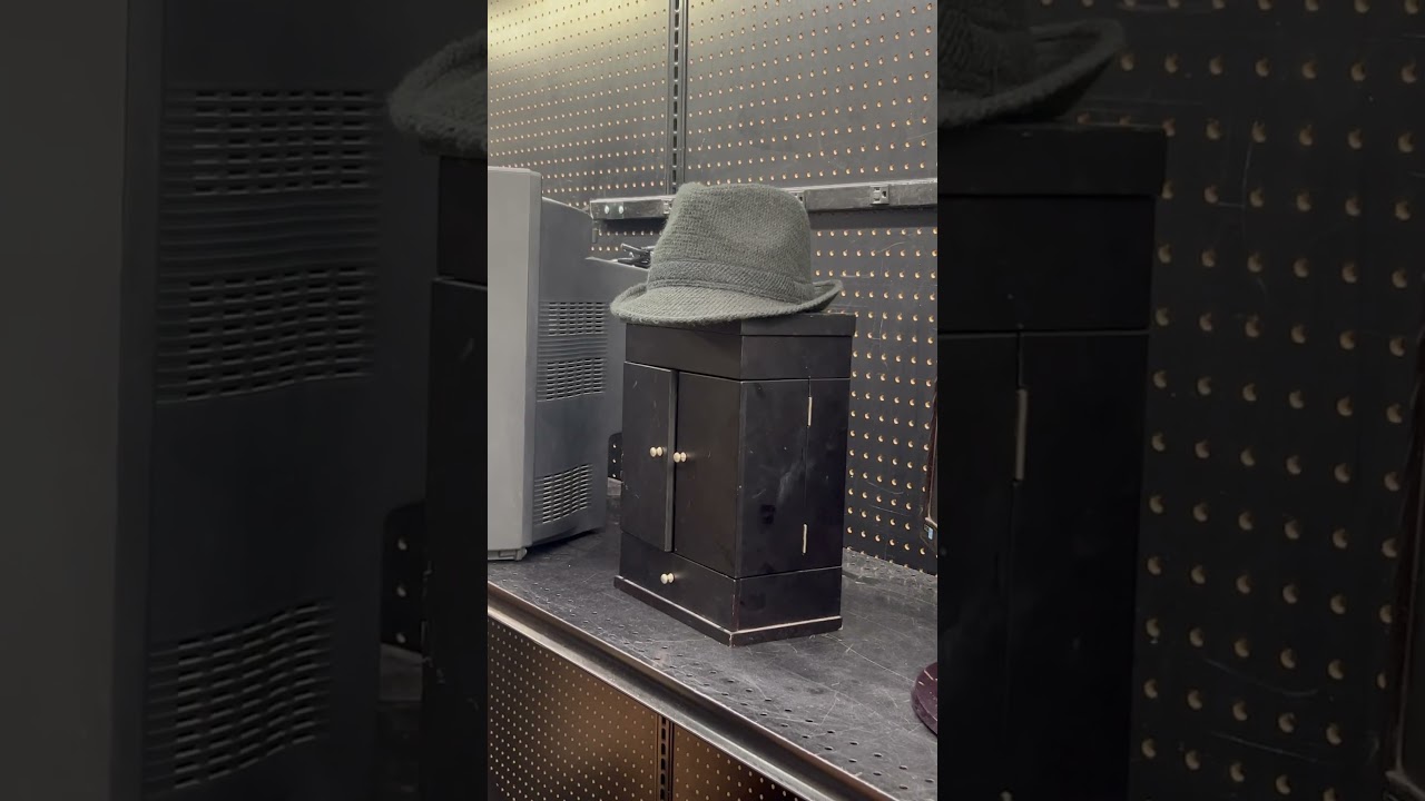 A fedora on a mini cabinet at the thrift store
