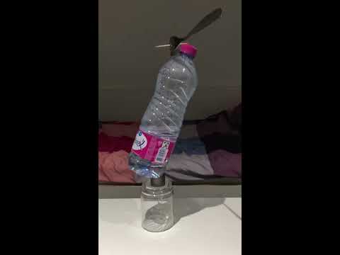        توازن قنينة مي على حافتها وفوقها متوازن شوكتين شوكة قنينة