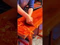 Scraping a beautiful wooden table surface using a small manual blade to create smooth final finish