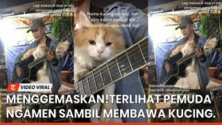 Adorable! A young man is seen busking while carrying a cat.