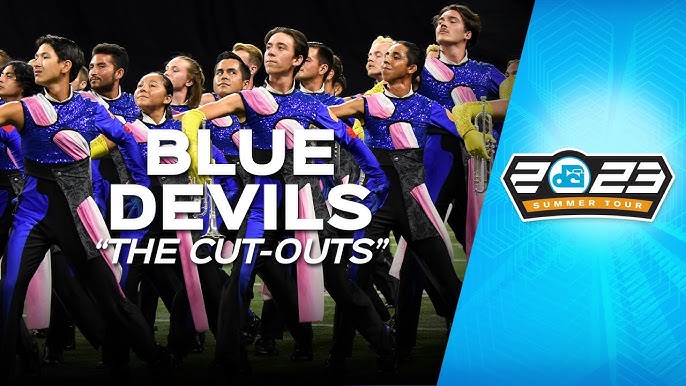 Image features a performance by a marching band known as the "Blue Devils," showcasing members wearing vibrant blue and pink uniforms. The text "BLUE DEVILS 'THE CUT-OUTS'" is prominently displayed, along with a logo for the 2023 DCI Summer Tour.