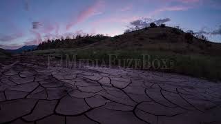 Stock Video - Sunset time lapse over dry cracked mud with pink clouds