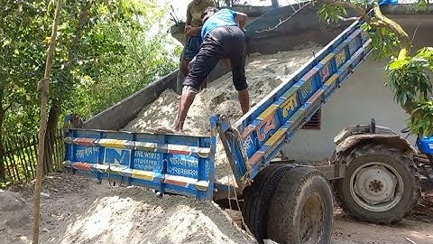 The river sand is being unloaded from the tractor by digital hydraulic system and by hand powertrac