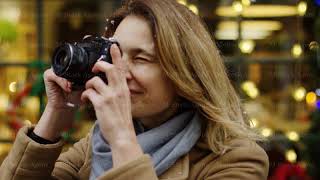 Attractive middle aged woman in casual style making photos on the camera while walking on the