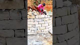 pounding and shaping natural stone blocks to build a sturdy circular wall #shorts