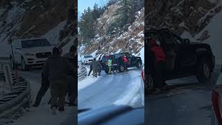 Group of people try to push Cadillac Escalade truck from behind on snowy icy road