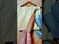carving textured patterns on light wood surface using a sharp gouge tool and blue safety gloves