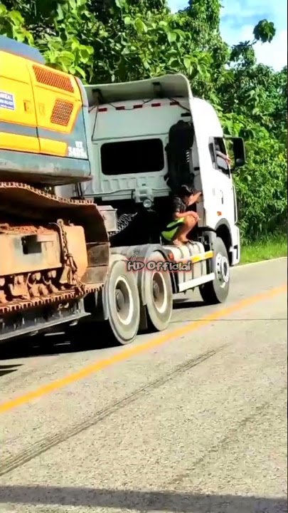 Truck FAW muatan alat berat santai di tanjakan sambil tarik truk SCANIA muatan