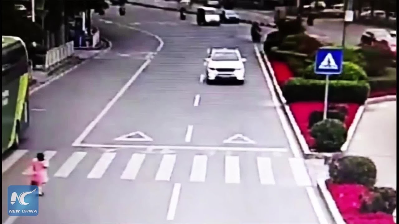 Polite girl bows to car driver after he stops to let her cross the road
