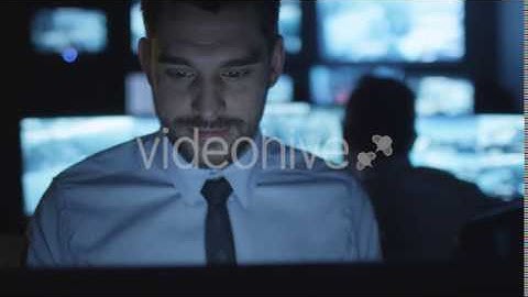 Focused Security Officer is Working on Computer in a Dark Monitoring Room | VideoHive 14743090