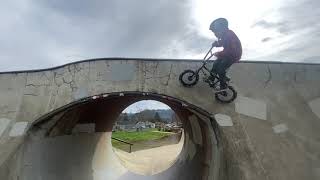Boy on bike rides over loop at skatepark then faceplants
