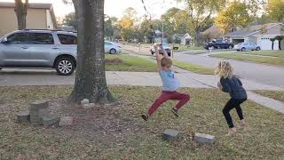 Boy swings on gymnastics rings rope swing held by tree and accidentally kicks girl on her face