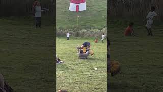 Two guys roll down grass hill and crash into little kid