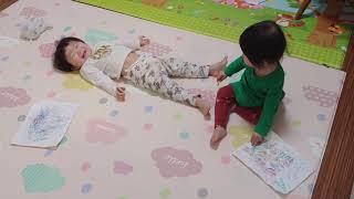 [Identical twins of 21 months]  Rolling around with a baby who focuses on drawing