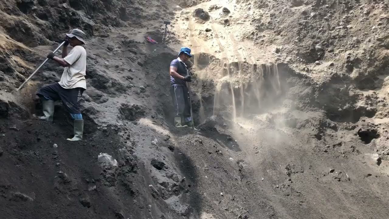 hard work..!!! miners collapsing the side of a sand cliff