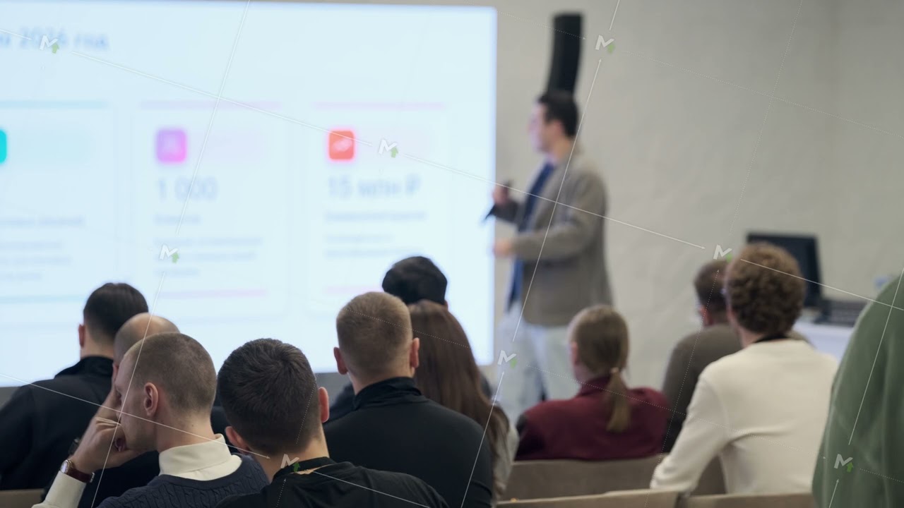 Presenter delivers lecture to seated audience during a business