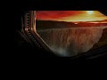 Spaceship parked by a noise blocking waterfall on a low gravity planet. Fades to black screen.