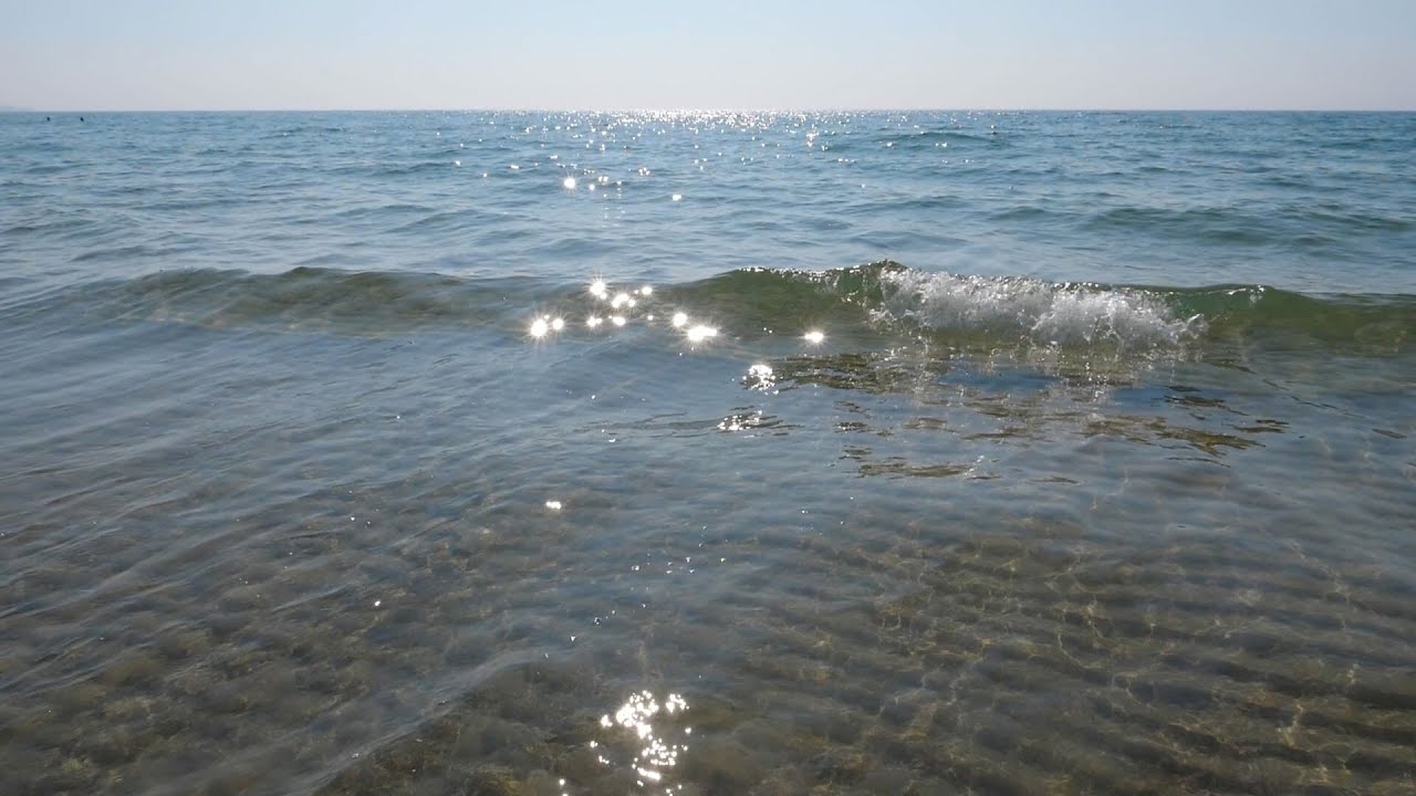 Beautiful sparkling summer lake with slow motion waves stock video. Rippled sand visible below. HD.