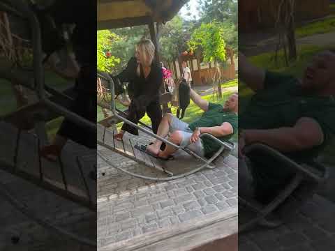 People are attempting to sit on some kind of crazy rocking chair!