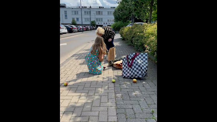 Little girl helps elderly lady to pick up apples