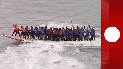 66 surfers ride giant board to break world record, California