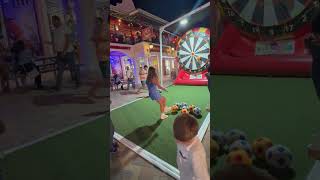Girl kicks soccer ball at bullseye then accidentally hits little boy on the head