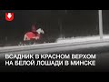 Человек в красном едет верхом на белой лошади в Минске