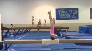 9 year old girl practicing her back extension roll on the beam
