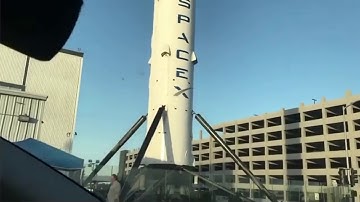 Elon Musk’s World: Tesla Model 3 leaving design studio, passing Hyperloop Tube, Falcon 9