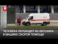 Человека переводят из автозака в машину скорой помощи