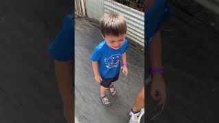 Boy runs away from chicken in coop