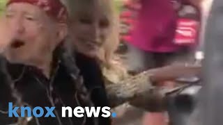 Dolly Parton and Willie Nelson ride a golf cart and wave to fans at Dollywood