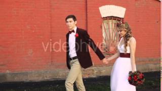 Bride and Groom Walking Along a Brick Red Wall