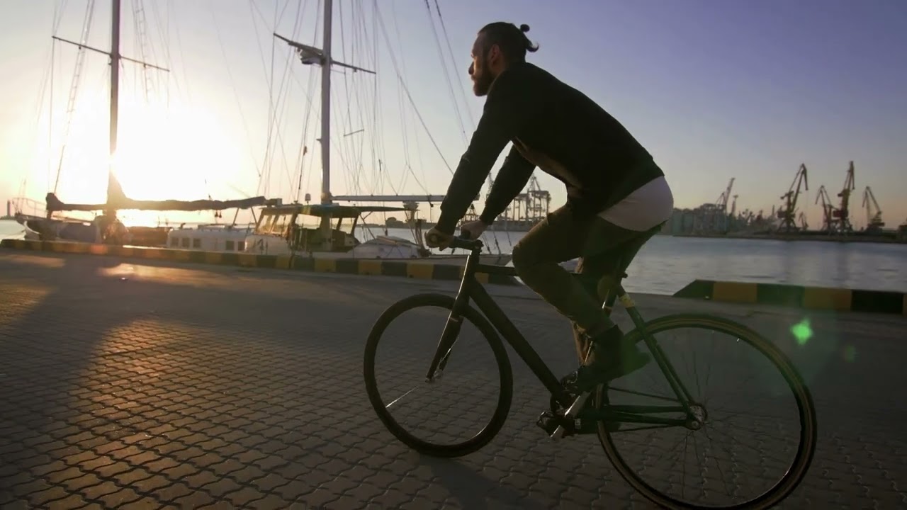 VideoVault Stock Video: Cyclist rides his bike along the harbor