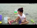 Vitória na areia da praia fazendo comidinha para a sua boneca cozinheira, fazendo bolo de chocolate