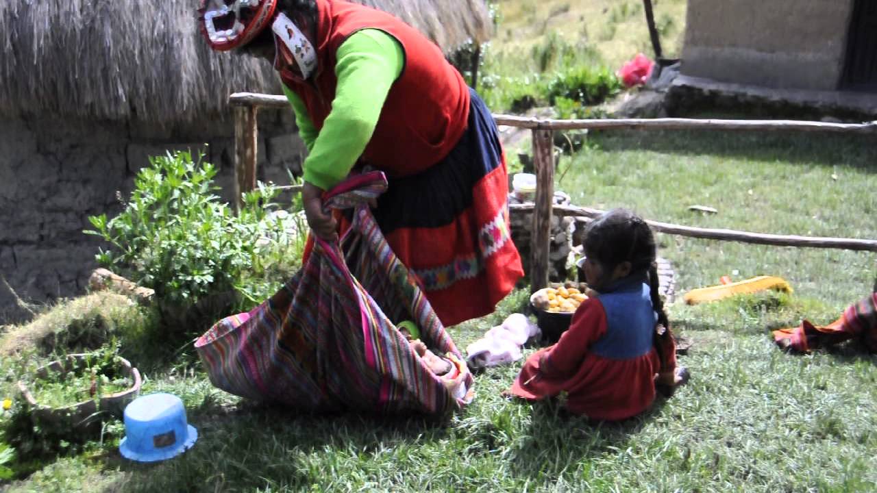 Quechua woman putting baby on her back