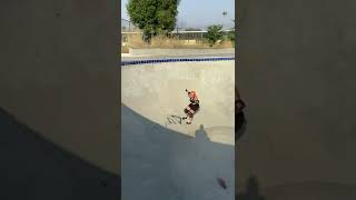 Girl drops into bowl at skatepark riding roller skates then falls and lands on her back (Angle 2/2)