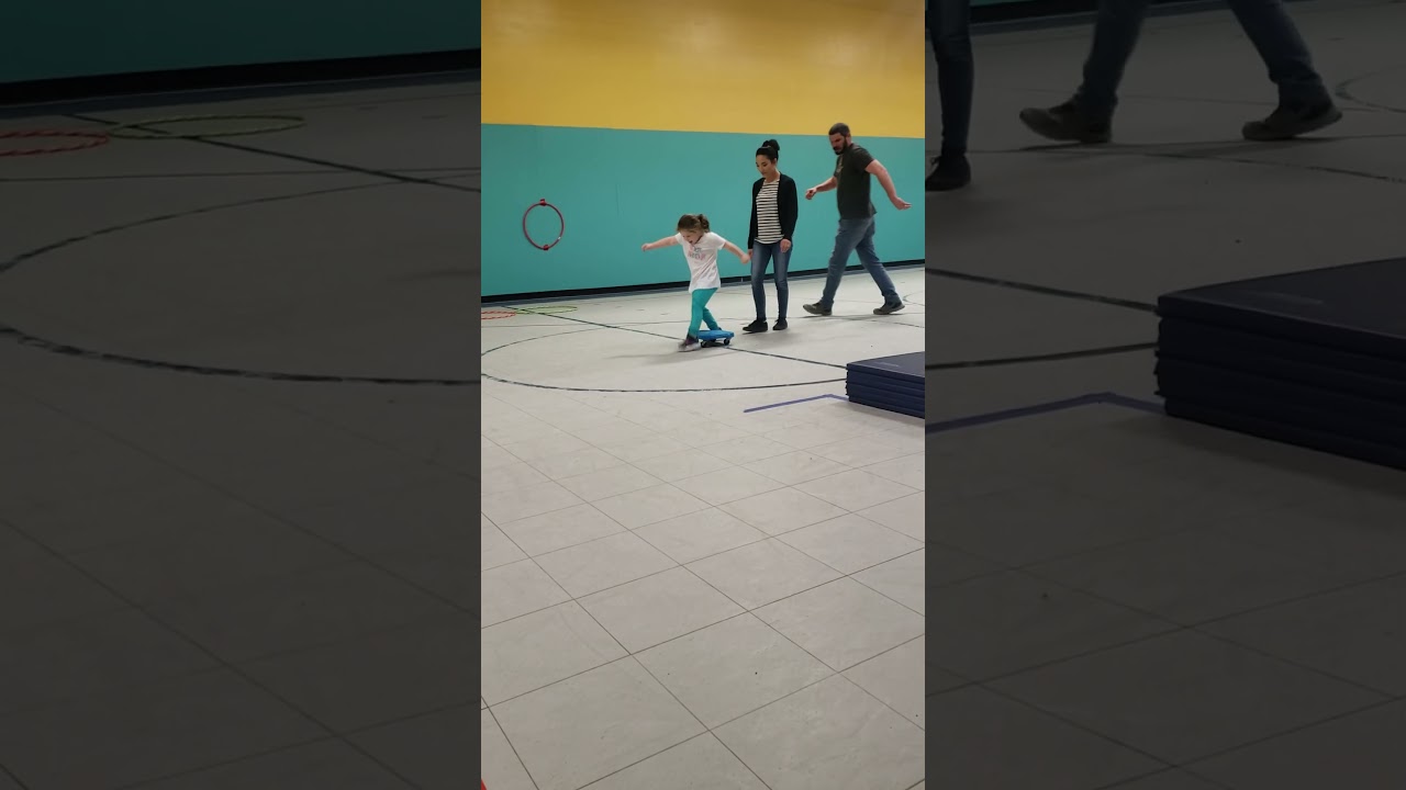 Girl runs around play area then slips and falls on back near hockey goal net