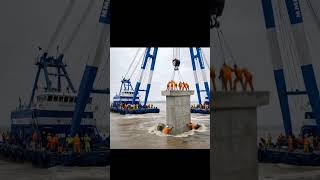 A heavy crane mounted on a barge is lifting and positioning a large precast concrete block. #b